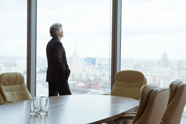 Uomo d'affari di mezza età che guarda fuori dalla finestra — Foto Stock