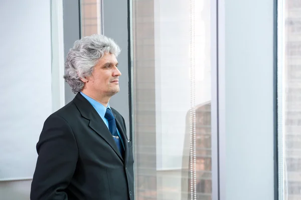 Geschäftsmann mittleren Alters schaut aus dem Fenster — Stockfoto