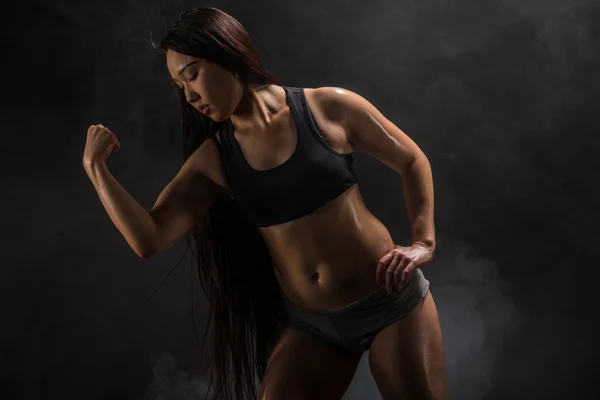 Jovem muscular mulher posando no preto — Fotografia de Stock