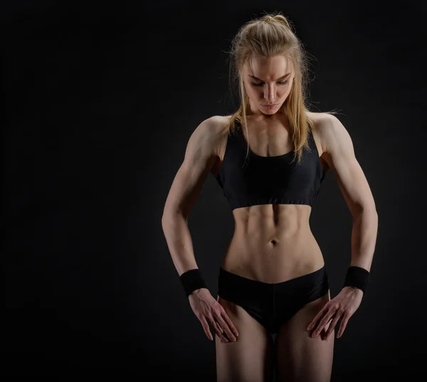 Young muscular woman posing on black — Stock Photo, Image