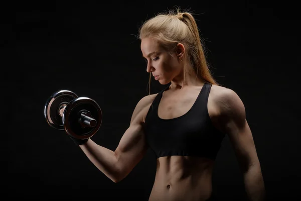 Young slim strong muscular woman posing in studio with dumbbell — Stock Photo, Image