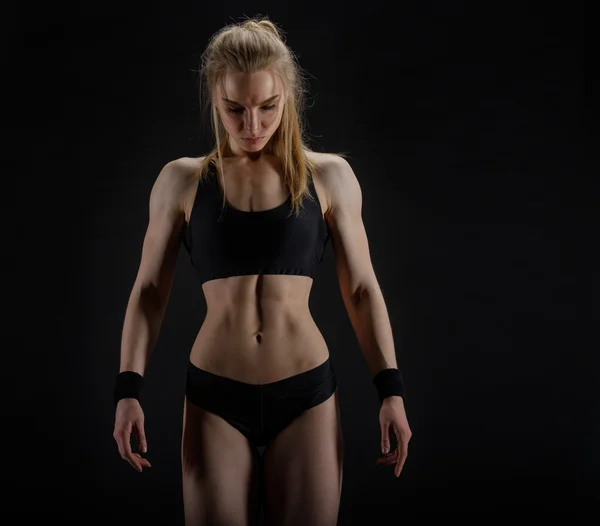 Ung muskulös kvinna poserar på svart — Stockfoto