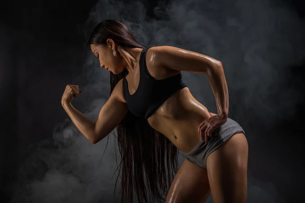 Jovem muscular mulher posando no preto — Fotografia de Stock