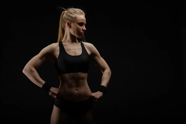 Young muscular woman posing on black — Stock Photo, Image