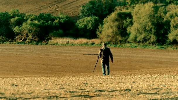 Natuurfotograaf lopen op een veld — Stockvideo