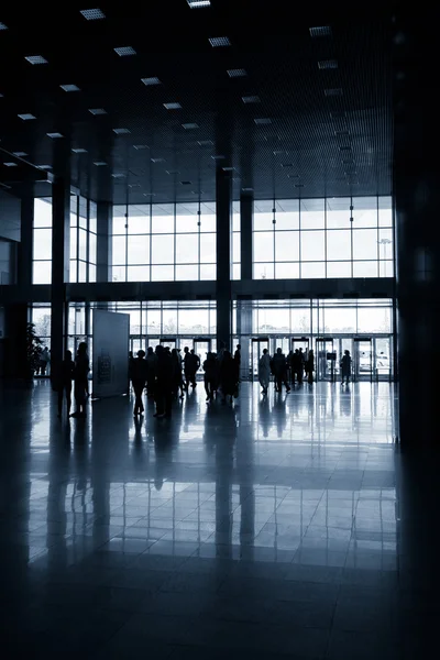 Silhouettes of people in modern hall — Stock Photo, Image