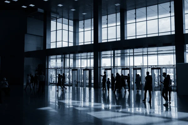 Silhouettes of people in modern hall — Stock Photo, Image