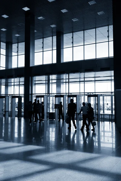 Silhouettes of people in modern hall — Stock Photo, Image