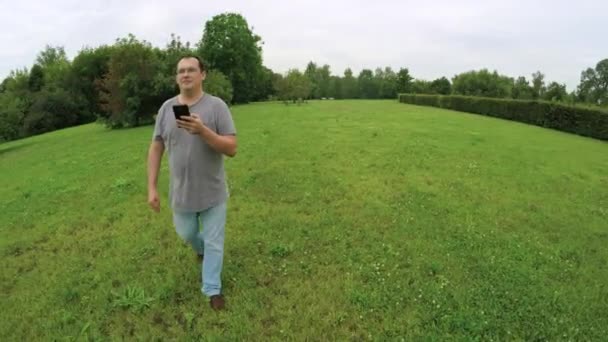 Uomo che cammina nel parco con smartphone — Video Stock