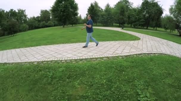 Чоловік гуляє в парку зі смартфоном — стокове відео
