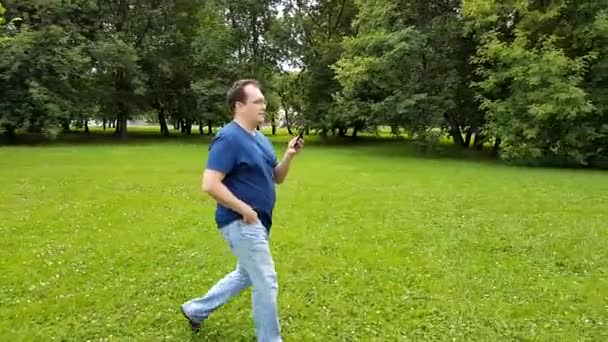 Uomo che cammina nel parco con smartphone — Video Stock