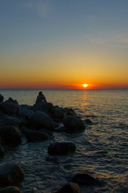 Deniz kıyısı taş oturan adam