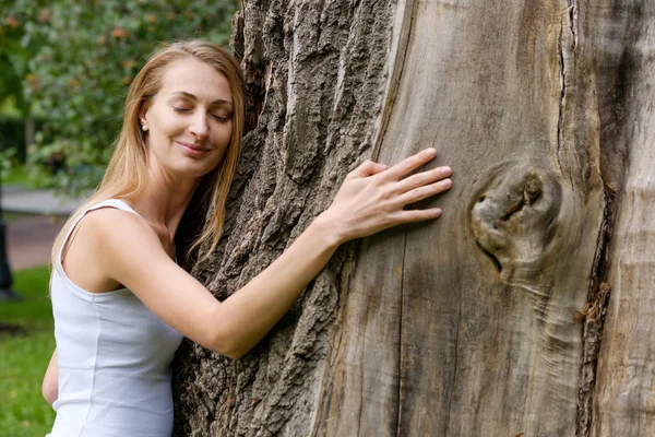Jovem mulher abraçando árvore grande — Fotografia de Stock