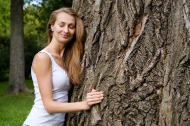 Genç kadın kucaklama büyük ağaç
