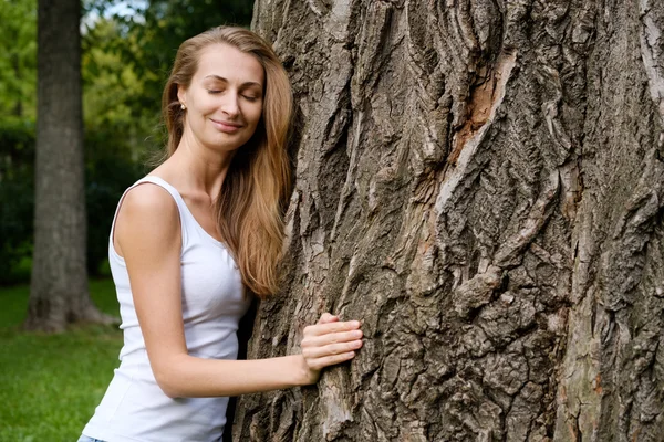Jonge vrouw knuffelen grote boom — Stockfoto