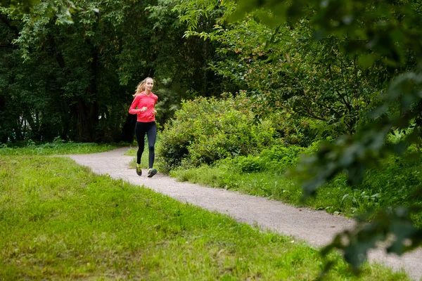 公園をジョギングしている若い女性が — ストック写真