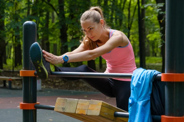 Fiatal vékony nő, nyúlik a edzőpálya — Stock Fotó
