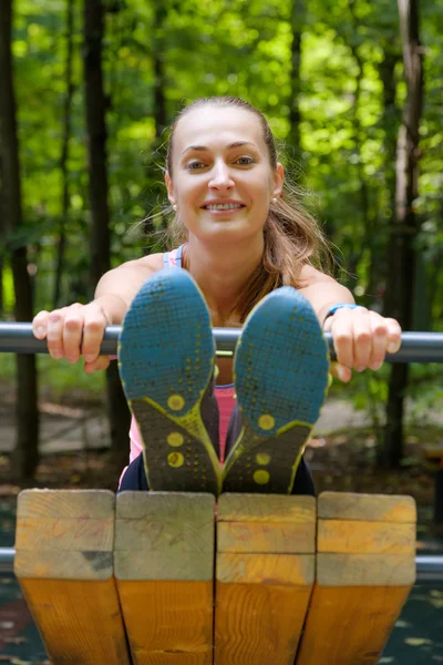 Jovem mulher magra que se estende em um campo de treinamento — Fotografia de Stock