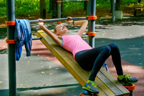 Joven mujer delgada haciendo ejercicio en el campo de entrenamiento —  Fotos de Stock