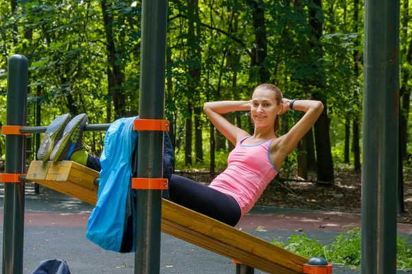 Joven mujer delgada haciendo ejercicio en el campo de entrenamiento —  Fotos de Stock