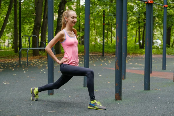 Joven mujer delgada haciendo ejercicio en el campo de entrenamiento — Foto de Stock