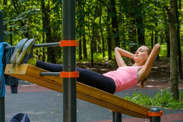 Joven mujer delgada haciendo ejercicio en el campo de entrenamiento —  Fotos de Stock