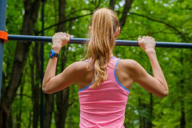 Genç ince kadın üzerinde yatay çubuk çeker