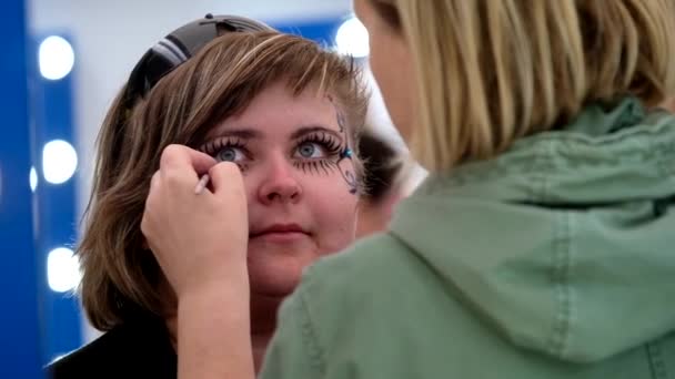 Художник наносит забавный макияж для женщины — стоковое видео