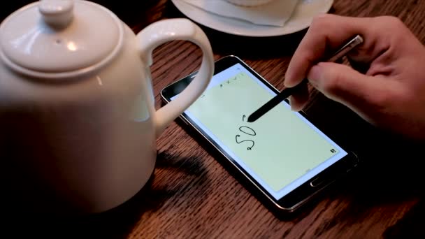 Человек пишет надпись SOS на экране смартфона — стоковое видео