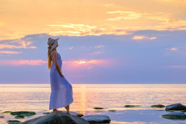 Gün batımında sahilde zarif bir kadın.