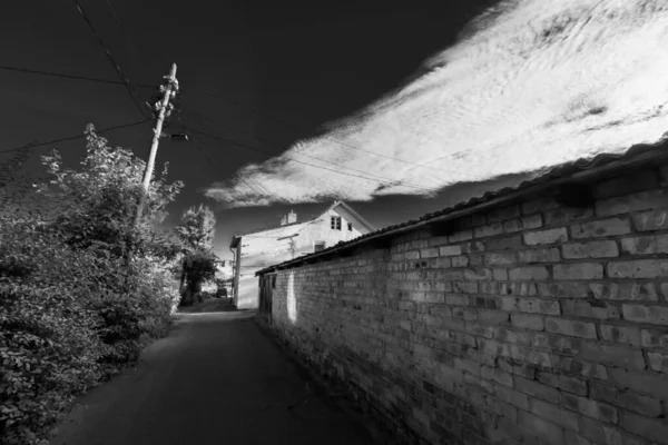 Smalle straat met stenen hek en huizen op het platteland — Stockfoto