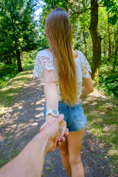 Young woman followed by boyfriend walking in forest — Stock Photo, Image