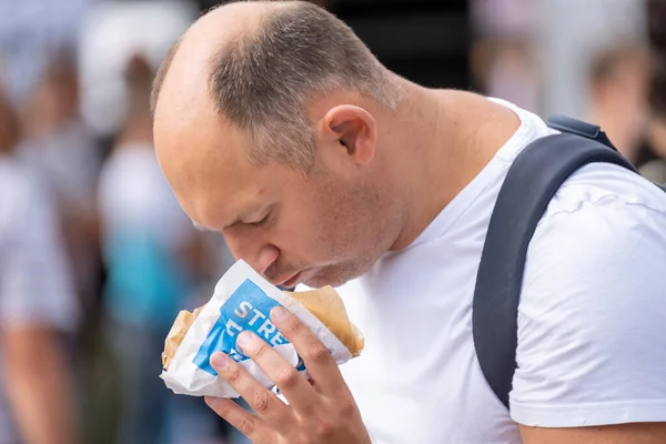 Uomo sovrappeso mangiare panino sulla strada — Foto Stock