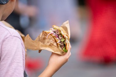 Lezzetli burgeri olan isimsiz bir çocuk.