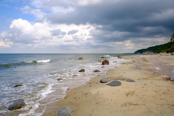 Wellenförmiges Meer und sandiges Ufer an bewölkten Tagen — Stockfoto