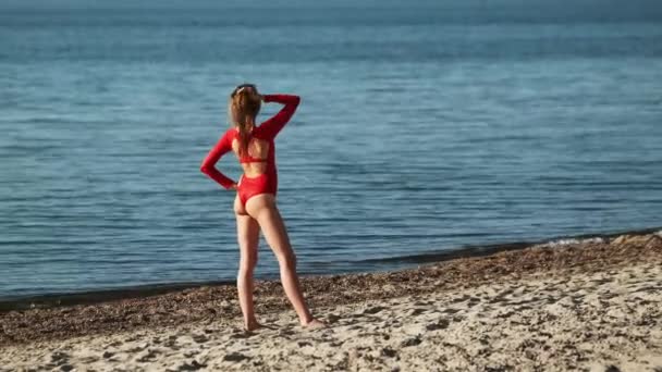 Стройная женщина в купальнике стоит на пляже — стоковое видео