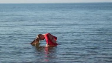 Genç kadın deniz suyunda eğleniyor.