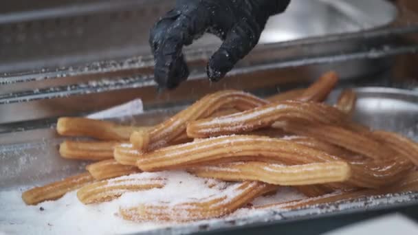 Повар катит чуррос в сахаре перед подачей — стоковое видео