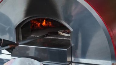 Ekin aşçısı sıcak fırında pizza pişiriyor.