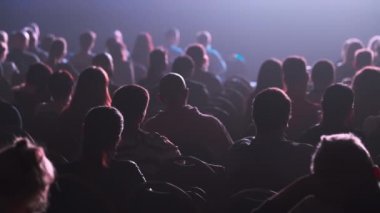 Dinleyiciler konferans salonundaki konuşmacının konuşmasını dinliyor.