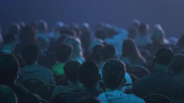 Dinleyiciler konferans salonundaki konuşmacının konuşmasını dinliyor.