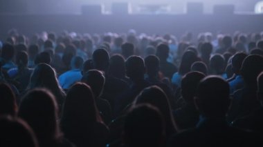 Dinleyiciler konferans salonundaki konuşmacının konuşmasını dinliyor.
