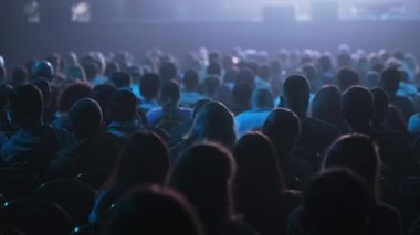 Dinleyiciler konferans salonundaki konuşmacının konuşmasını dinliyor.