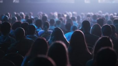 Dinleyiciler konferans salonundaki konuşmacının konuşmasını dinliyor.
