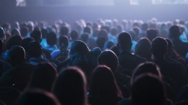 Dinleyiciler konferans salonundaki konuşmacının konuşmasını dinliyor.