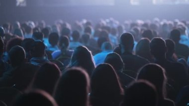 Dinleyiciler konferans salonundaki konuşmacının konuşmasını dinliyor.