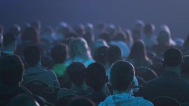 Dinleyiciler konferans salonundaki konuşmacının konuşmasını dinliyor.