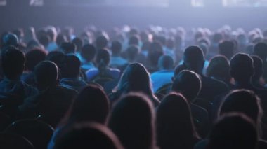 Dinleyiciler konferans salonundaki konuşmacının konuşmasını dinliyor.