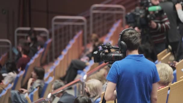 Videógrafo em máscara protetora trabalhando em auditório — Vídeo de Stock