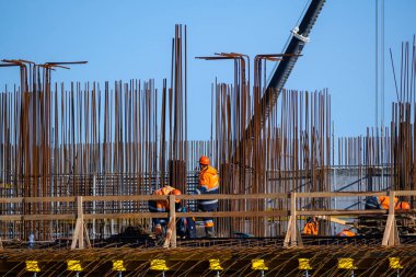 Köprüde, metal direklerin yanında tanınmayan işçiler.